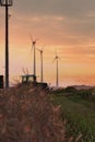 Beautiful shot of a tractor working in the fields of wheat with wind power plants in the background Royalty Free Stock Photo