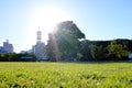 Beautiful shot of trees in a grassy field with buildings and a clear sky in the background Royalty Free Stock Photo
