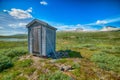 Beautiful shot of a wooden portable bathroom in the center of a green field