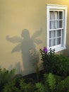 Beautiful shot of a young female shadow with wings on a house yellow facade background