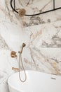 A beautiful shower with marble walls and gold faucet.