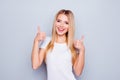 Beautiful shy smiling happy woman with straight long hair is showing thumbs up against grey background Royalty Free Stock Photo