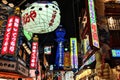 Beautiful signs lit up in the Shinsekai district of Osaka, with the Tsutenkaku tower standing tall in the background.