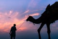 Beautiful silhouette of a person with a camel during sunset on the desert of Jaisalme