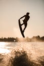 beautiful silhouette of wakeboarder athlete man jumping high making tricks in the air Royalty Free Stock Photo