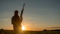 Silhouette of woman hunter. It stands in a picturesque place with a gun at sunset. Sports shooting and hunting concept Royalty Free Stock Photo