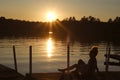 Silhouette of young child at sunset on a lake dock with at sundown.