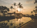 Beautiful silhouettes of palm tress reflecting in water of swimming pool at sunset Royalty Free Stock Photo