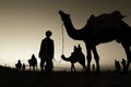 Beautiful silhouettes of people and camels on a desert