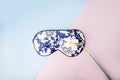 Beautiful silk sleep mask for eyes with flowers pattern and white narcissus or daffodil flower on a pink blue background