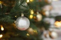 Beautiful silver Christmas ball hanging on fir tree branch against blurred background, closeup. Space for text Royalty Free Stock Photo