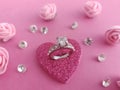 Beautiful silver and diamond engagement ring on a pink heart with pink roses and loose diamonds on a pink background Royalty Free Stock Photo