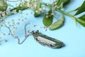 Beautiful silver necklace with nephrite gemstone and flowers on blue background