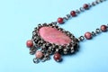 Beautiful silver necklace with rhodonite and tourmaline gemstones on blue background, closeup