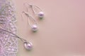 Beautiful silver shiny pearl jewelry, trendy glamorous earrings, chain on pink purple background with exquisite lace. Flat lay,