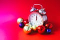 Beautiful silver vintage alarm clock and set of red, blue and golden Christmas balls on a bright red background Royalty Free Stock Photo