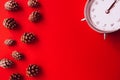 Beautiful silver vintage alarm clock and spruce cones on a bright red background