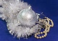 Beautiful silvery New Year`s ball, brilliant tinsel and silver cones on a blue background - New Year`s composition Royalty Free Stock Photo