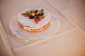 Beautiful simple wedding cake with fruits on table at wedding reception outdoors in the evening.Delicious little wedding cake in Royalty Free Stock Photo