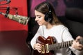 Beautiful singer playing guitar in radio station
