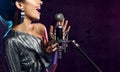 Beautiful singing girl curly afro hair. Beauty woman singer sing with microphone karaoke song on stage smoke, spotlights Royalty Free Stock Photo