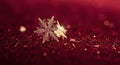 A beautiful single snowflake with golden highlights on a deep red backdrop Royalty Free Stock Photo
