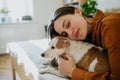 Beautiful single woman lying on bed, snuggling, petting her dog, enjoying weekend. Young woman living alone in apartment Royalty Free Stock Photo