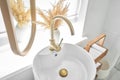 Close-up of an elegant golden faucet in the bathroom sink next to stylish decorations. A beautiful sink with a golden Royalty Free Stock Photo