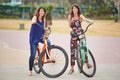 Beautiful sisters posing together on their colourful bicycles outdoors