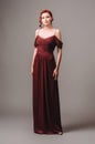 Beautiful skinny ginger girl in a burgundy evening gown