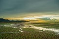 Beautiful sky during sunset, Cracked ground with small green grass and little water flow leading to river.