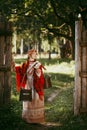 Beautiful Slavic girl with long blonde hair and brown eyes in a white and red embroidered suit and a yoke on her