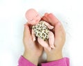 Beautiful sleeping newborn baby doll in the palms of a child, white raised background. Royalty Free Stock Photo