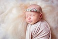 Beautiful sleeping newborn girl with a bandage of flowers on her head Royalty Free Stock Photo