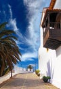 Beautiful sleepy canarian village, empty alley, bright white house traditional wooden balcony, palm tree, blue sky - La Oliva,