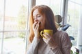 Beautiful sleepy smiling young red haired girl with yellow cup of fresh morning coffee