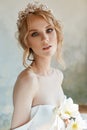 Beautiful slender blonde in the evening sun in a long white dress. Portrait of a woman with a flower in her hand. Perfect