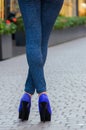 Beautiful slender female legs in tight jeans and blue shoes on a Royalty Free Stock Photo