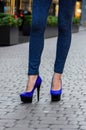 Beautiful slender female legs in tight jeans and blue shoes on a Royalty Free Stock Photo