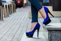 Beautiful slender female legs in tight jeans and blue velvet high-heeled shoes Royalty Free Stock Photo