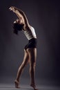 Beautiful slender girl athlete dancing barefoot under studio searchlights wearing high waist panties and white top Royalty Free Stock Photo