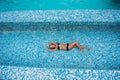 Beautiful slender girl with blond hair in a swimsuit lying in the pool, top view Royalty Free Stock Photo