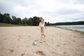 A beautiful slender girl with long blond hair and long legs runs along the beach towards a soccer ball Royalty Free Stock Photo