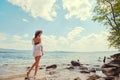 Beautiful slender girl relaxing on the rocky beach of a large lake Royalty Free Stock Photo