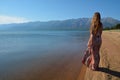 Beautiful, slender girl standing on the shore of Lake Baikal and