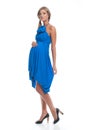 Beautiful slender pregnant model in a blue dress sarafan on a white background.