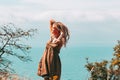 Beautiful slender tattooed woman with blonde dreadlocks in a dress rejoices on a hill. Sea View Travel and Vacation lifestyle