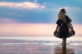 A girl with blond chic hair in a black bikini and a lace shawl walks along the estuary Royalty Free Stock Photo