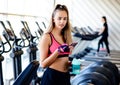 Beautiful athletic girl in the sportswear uses the fitness app on your smartphones in the gym. Athlete enjoys her training. Royalty Free Stock Photo