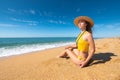 Beautiful slim and attractive caucasian young woman in a yellow swimsuit and top wearing a straw hat enjoys the sea Royalty Free Stock Photo